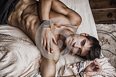 Shirtless male model lying alone on his bed Stock Photo