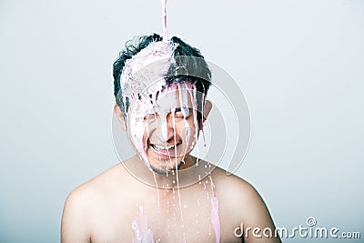 Shirtless young man with pink paint falling on his head against gray background Stock Photo