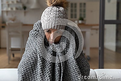 Shivering young lady feel cold sit on sofa in plaid Stock Photo