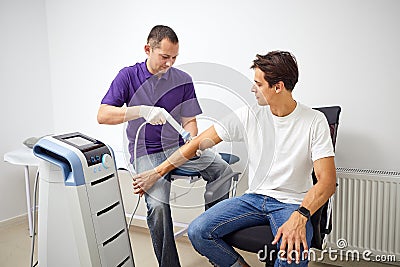 Shock wave therapy. Physiotherapist doctor uses medical equipment for highly effective epicondylitis, pain and inflammation treat Stock Photo