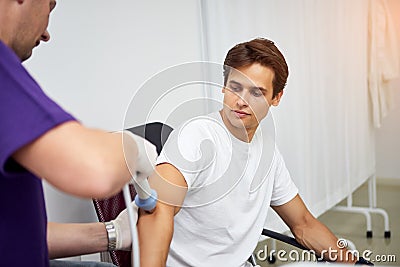 Shock wave therapy. Physiotherapist doctor uses medical equipment for highly effective epicondylitis, pain and inflammation treat Stock Photo