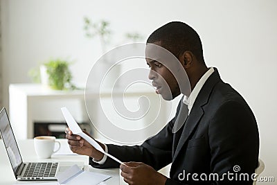 Shocked African American reading received printed documentation Stock Photo