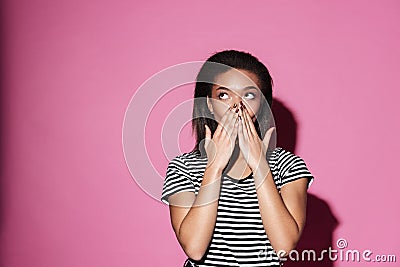 Shocked african girl looking away and covering her mouth Stock Photo