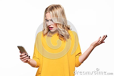 Shocked angry young woman looking at her mobile phone in disbelief. Woman staring at shocking text message on her phone. Stock Photo