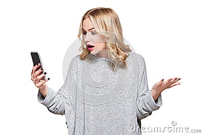 Shocked angry young woman looking at her mobile phone in disbelief. Woman staring at shocking text message on her phone. Stock Photo