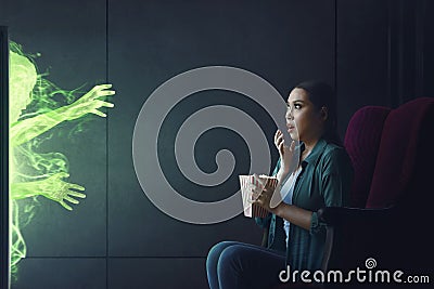 Shocked asian woman watching scary movie with popcorn Stock Photo