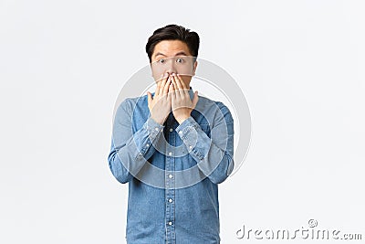 Shocked astounded asian man witness accident, gasping and cover mouth, gossiping with coworkers at office, hear stunning Stock Photo