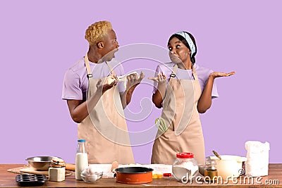 Shocked black guy holding dough and his ignorant girlfriend shrugging shoulders on violet studio background Stock Photo