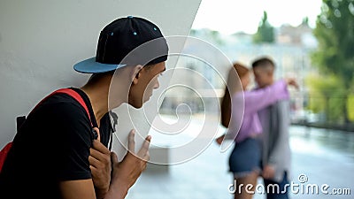 Shocked black teen guy looking girlfriend hugging classmate, unrequited love Stock Photo