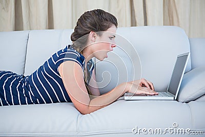 Shocked brunette looking her laptop Stock Photo