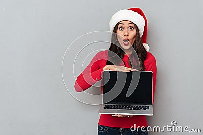 Shocked brunette woman in red blouse and christmas hat Stock Photo