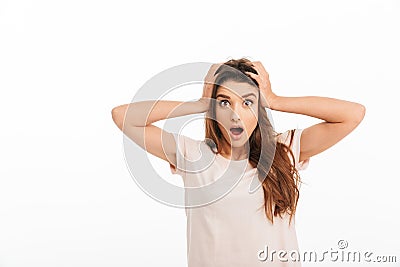 Shocked brunette woman in t-shirt holding her head Stock Photo