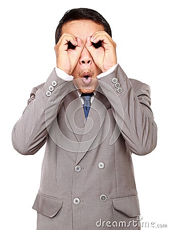 Shocked businessman looking through his circled fingers Stock Photo