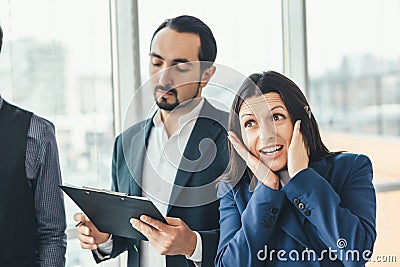 Shocked businesswoman, keeping hands on cheeks, looking at the camera, expressing despair and surprise while serious Stock Photo