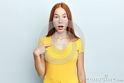 Shocked cute student with freckle , long red hair pointing at herself Stock Photo
