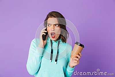 Shocked displeased young woman posing isolated over purple background wall talking by mobile phone Stock Photo