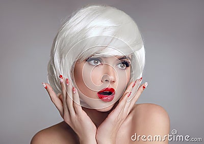 Shocked face. Blond Woman with red lips and manicure nails surprise holds cheeks by hand. Beautiful girl with white short bob Stock Photo
