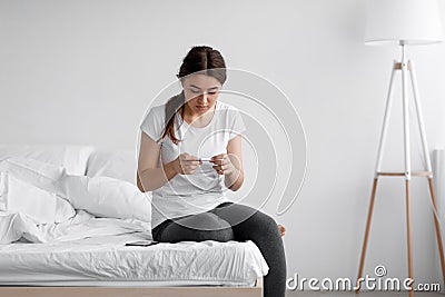 Shocked frustrated scared european young female looking at pregnancy test and upset about result Stock Photo