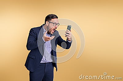 Shocked frustrated young male professional manager dressed in elegant suit looking at mobile phone and gesturing. Business manager Stock Photo