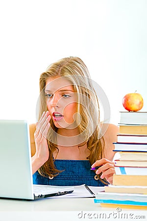 Shocked girl sitting at desk and looking on laptop Stock Photo