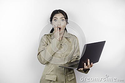 Shocked government worker woman holding her laptop with her mouth wide open. PNS wearing khaki uniform Stock Photo