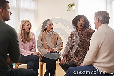 Shocked Group Consoling Man Speaking At Support Group Meeting For Mental Health Or Dependency Issues Stock Photo