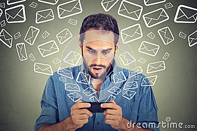 Shocked man busy sending messages emails from smart phone email icons flying of mobile phone Stock Photo