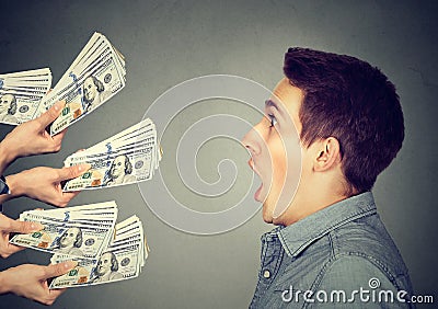 Shocked man looking at many hands offering money dollar bills Stock Photo