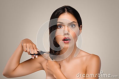 Shocked millennial european naked woman cuts hair with scissors Stock Photo