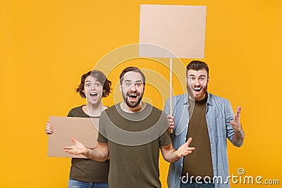 Shocked protesting young three people guys girl hold protest signs broadsheet blank placard on stick spreading hands Stock Photo