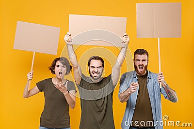 Shocked protesting young three people hold protest signs broadsheet blank placard on stick point on camera screaming Stock Photo