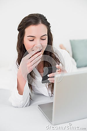 Shocked smiling woman looks at mobile phone in bed Stock Photo