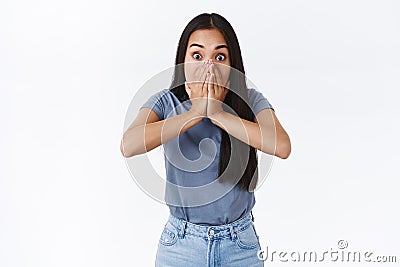 Shocked, speechless asian brunette girl staring camera astonished, gasping, hold her mouth not scream from shook and Stock Photo