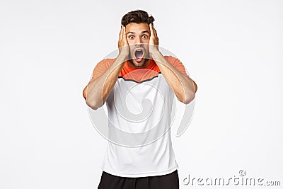 Shocked, speechless handsome mascular male athlete in sports t-shirt, gasping, drop jaw concerned and astonished, grab Stock Photo