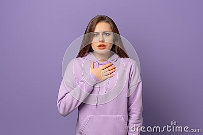 Shocked and startled young brunette woman watching smth cringe, grimacing and staring awkwardly at camera, standing over purple Stock Photo
