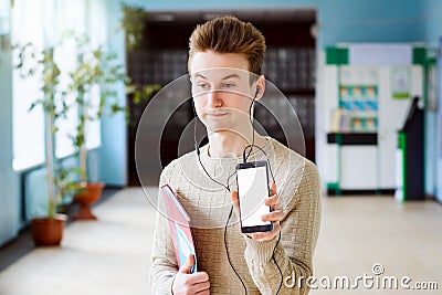 Student showing screen of mobile phone to the camera looks bewildered Stock Photo