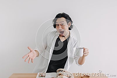 Shocked and surprised face man reading magazine and drink coffee. Stock Photo