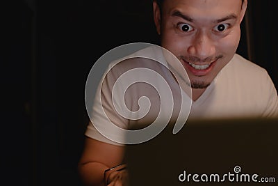 Shocked and surprised funny face of man watch the laptop alone at night. Stock Photo