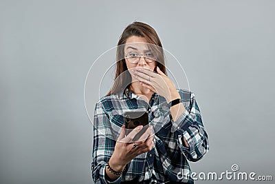 Shocked woman with glasses is talking on phone that looks like an iPhone Stock Photo