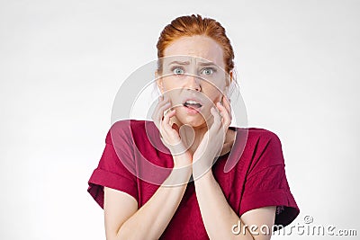 Shocked woman looking at camera with open mouth and touching head Stock Photo