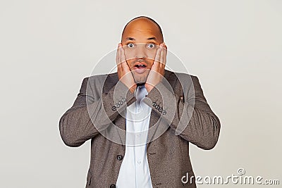 Shocked young african american guy businessman expressing surprise and amazement, touching his face and folding his lips, stands Stock Photo