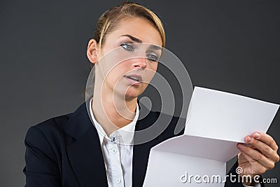 Shocked Young Businesswoman Reading Letter At Desk Stock Photo