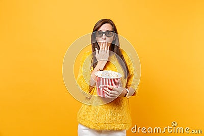 Shocked young girl in 3d imax glasses covering mouth with palm watching movie film holding bucket of popcorn isolated on Stock Photo