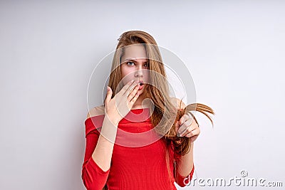 shocked young girl dissatisfied by dry hair with split ends, annoyed, isolated on white Stock Photo