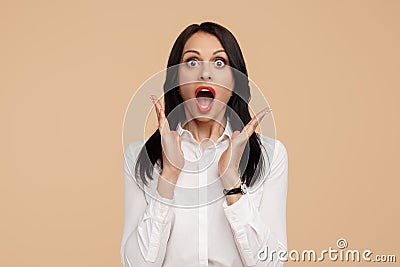 Shocked young modern business woman with hands up over beige background. Success and winner concept. Stock Photo