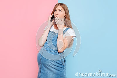 Shocked young pregnant girl talking on her smartphone Stock Photo