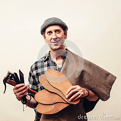 Shoemaker modeling shoe at his workshop. Small business concept. Handmade leather shoes. Cobbler holding set of tools and leather Stock Photo