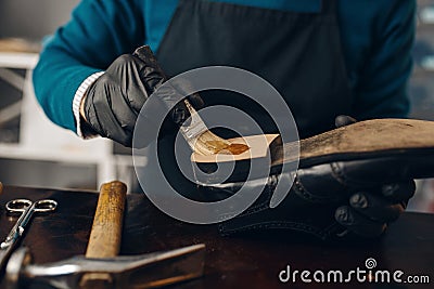 Shoemaker smears glue to the shoe, footwear repair Stock Photo