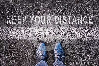 Shoes with message `Keep your distance` on asphalt ground Stock Photo