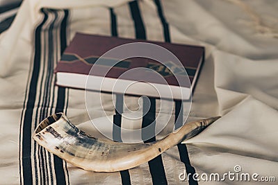 A shofar is placed on a tallit next to a close Torah study book. Before the Jewish holidays on the month Stock Photo